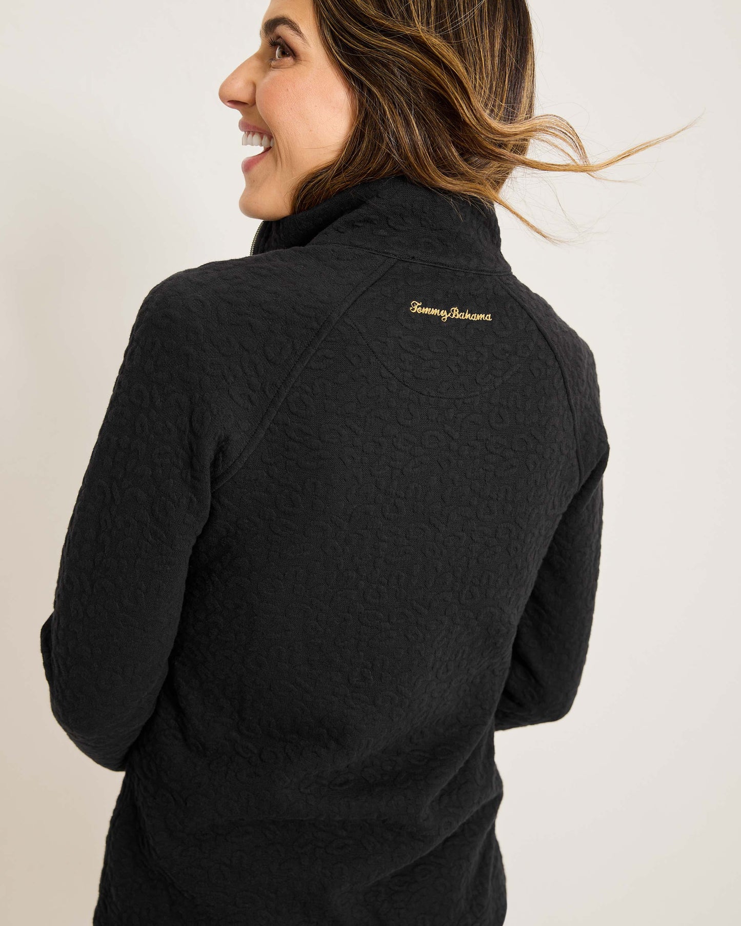 Hannahs Of Erin- Erin Ontario-Tommy Bahama -Aruba Sweatshirt- Style # SW222047 colour black featuring a zip-up design, mock neckline, and zippered pockets, adorned with a jacquard animal print. Made from a blend of 63% cotton, 35% recycled polyester, and 2% spandex, this sweatshirt offers a touch of stretch for comfort. An eco-friendly and stylish choice, perfect for all-day wear.