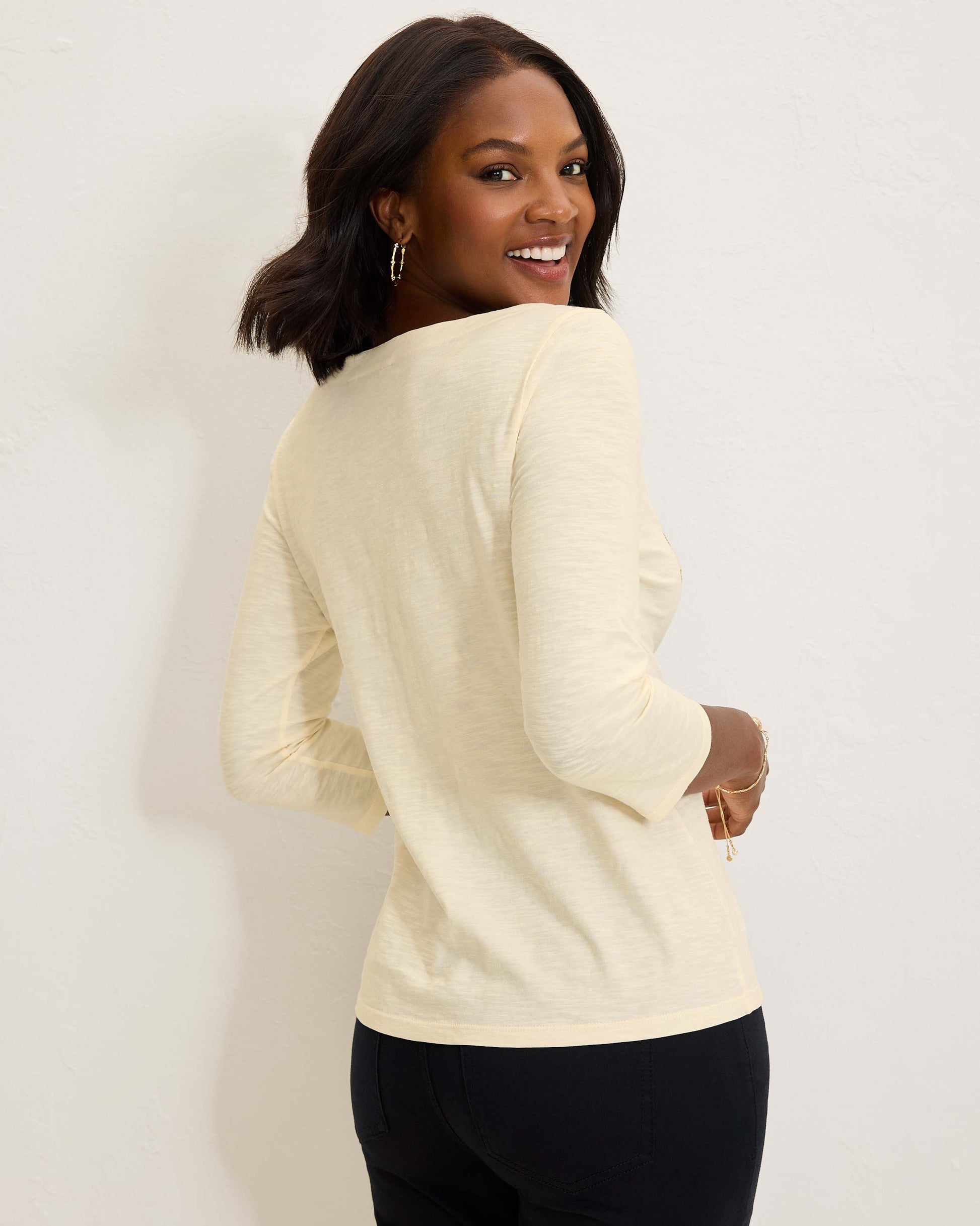 Hannahs Of Erin- Erin Ontario-Puerta Del Sol Lux 3/4-Sleeve T-Shirt-SW221998 100% organic cotton – breathable, sustainable, and ultra-soft.
 Features a delicate palm tree motif with shimmering gold embroidery & embellishments for a luxe touch.
Classic silhouette with 3/4 sleeves and a round neckline for a polished, versatile look.
 Available in soft ivory,  – timeless and easy to style.
Perfect Length