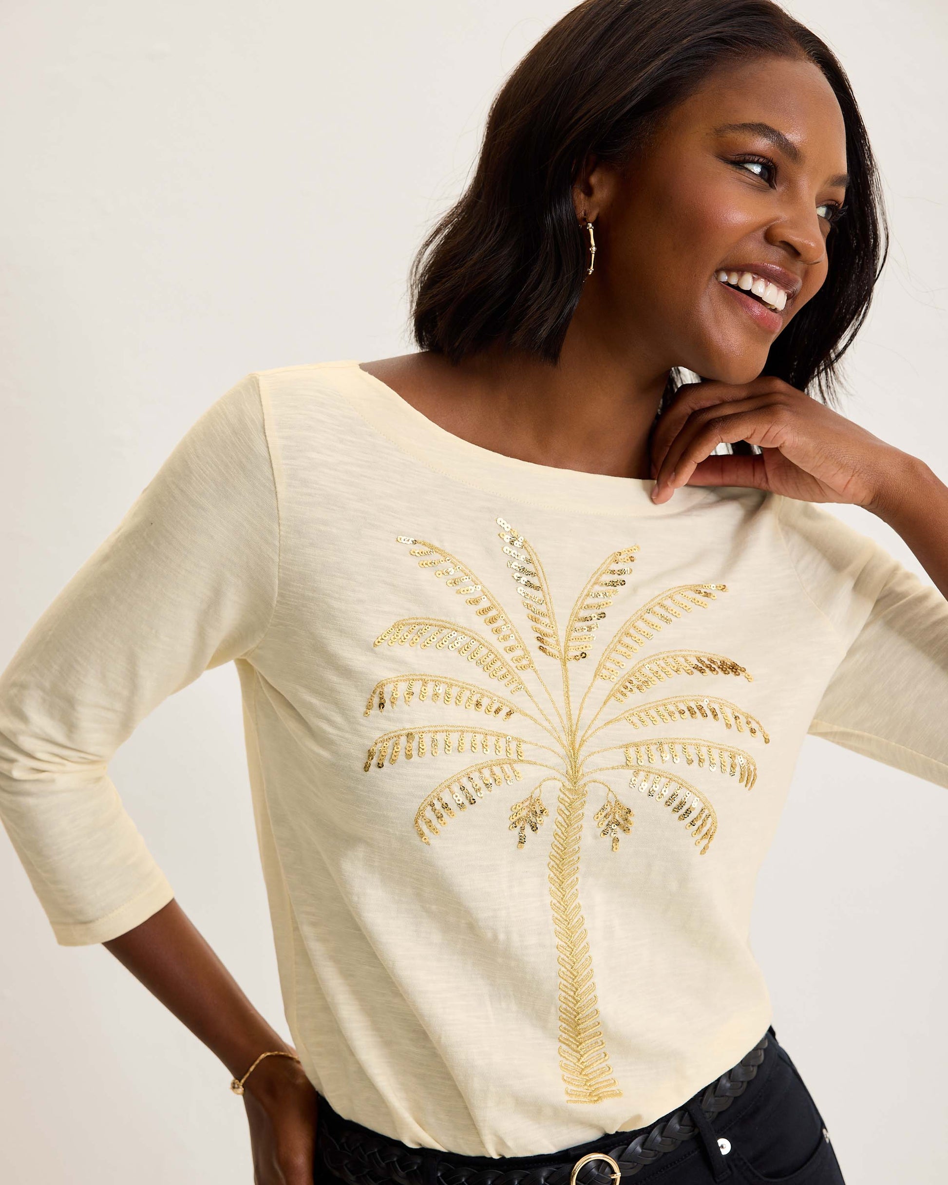 Hannahs Of Erin- Erin Ontario-Tommy Bahama-Puerta Del Sol Lux 3/4-Sleeve T-Shirt-SW221998 100% organic cotton – breathable, sustainable, and ultra-soft.
 Features a delicate palm tree motif with shimmering gold embroidery & embellishments for a luxe touch.
Classic silhouette with 3/4 sleeves and a round neckline for a polished, versatile look.
 Available in soft ivory,  – timeless and easy to style.
Perfect Length: 24.5" back length (Size S) 