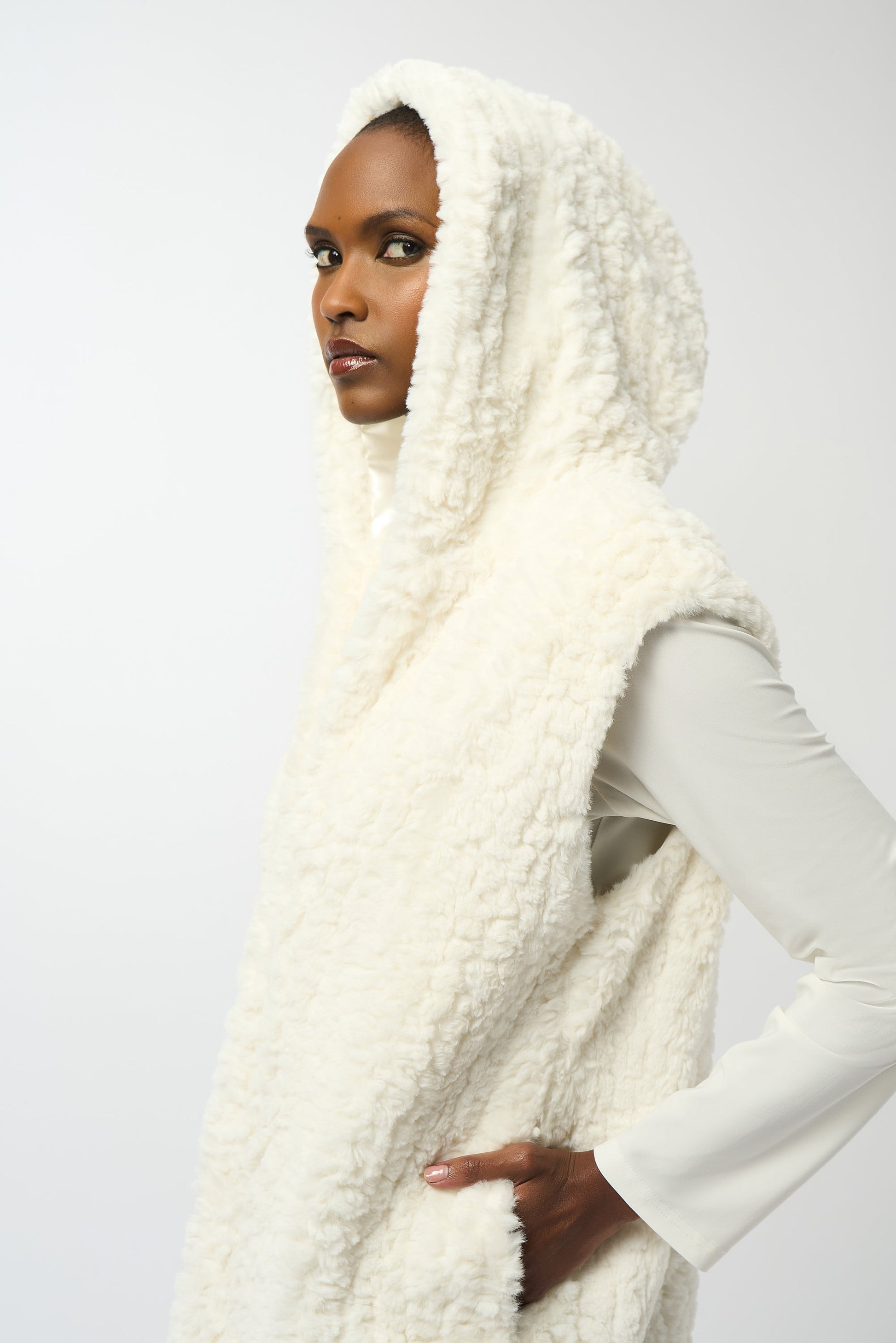 Hannahs Of Erin| Erin Ontario | Joseph Ribkoff | Faux Fur Textured Stripe Vest| colour Vanilla. Joseph Ribkoff sleeveless faux fur vest with textured stripe pattern, hooded collar, discreet hook-and-eye closure, and full lining, offering plush warmth and sophisticated layering.