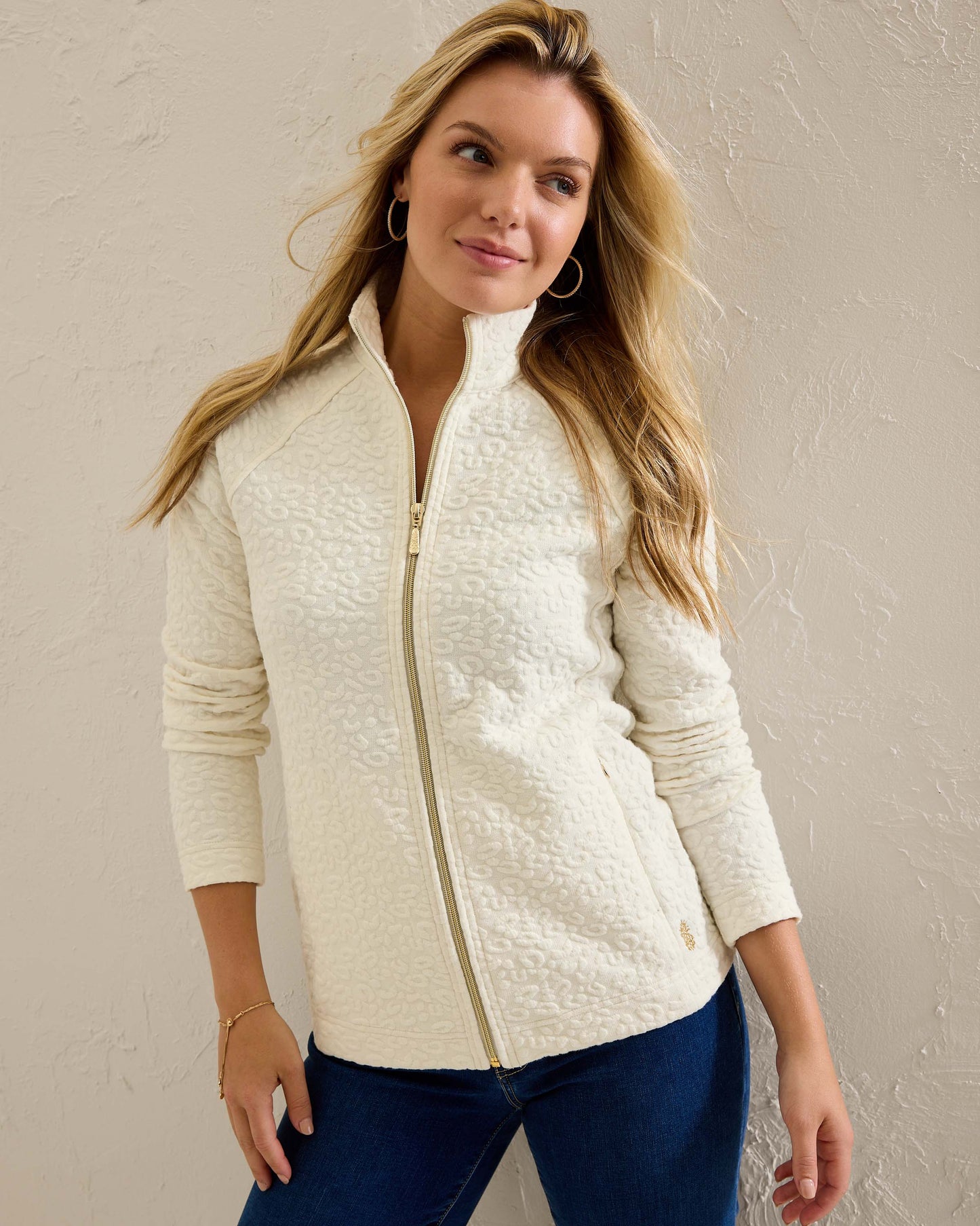 Hannahs Of Erin- Erin Ontario-Tommy Bahama -Aruba Sweatshirt- Style # SW222047  colour coconut (off white) featuring a zip-up design, mock neckline, and zippered pockets, adorned with a jacquard animal print. Made from a blend of 63% cotton, 35% recycled polyester, and 2% spandex, this sweatshirt offers a touch of stretch for comfort. An eco-friendly and stylish choice, perfect for all-day wear.